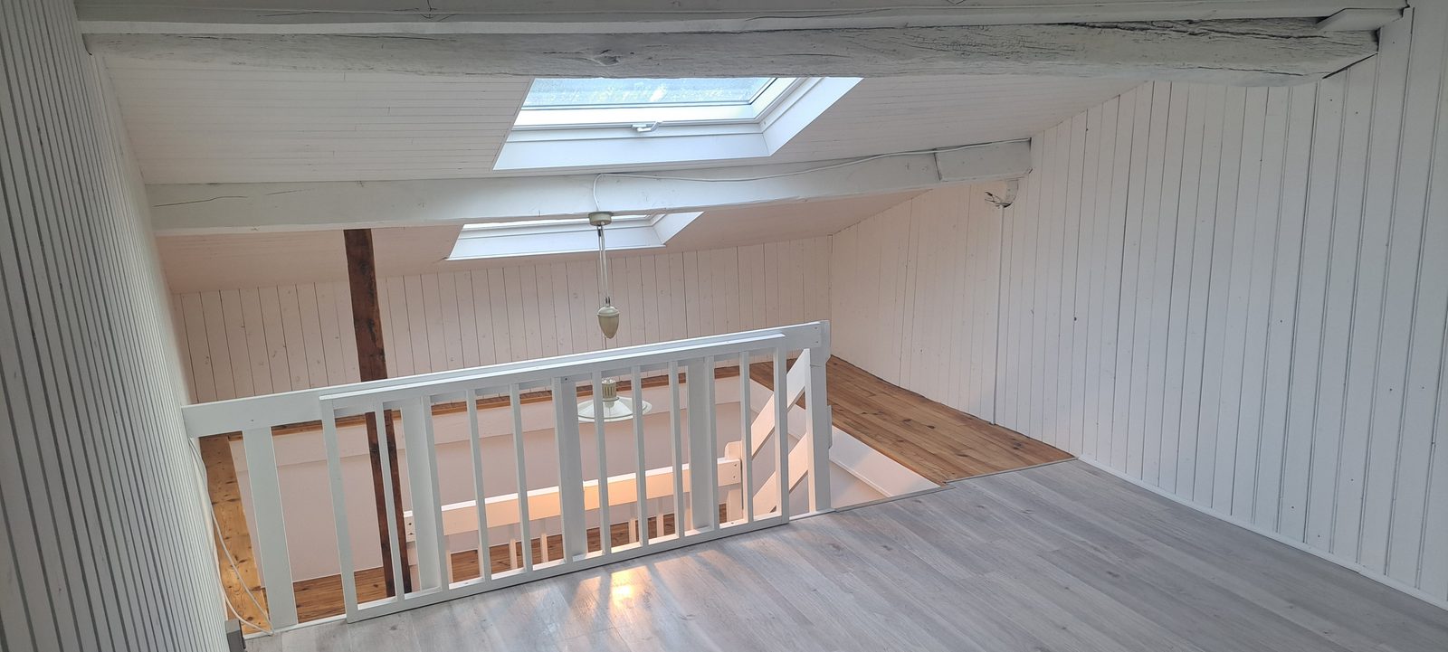 Combles rénovés à Eybens : lambris peint en blanc, sol stratifié clair, garde-corps neuf et fenêtres de toit
