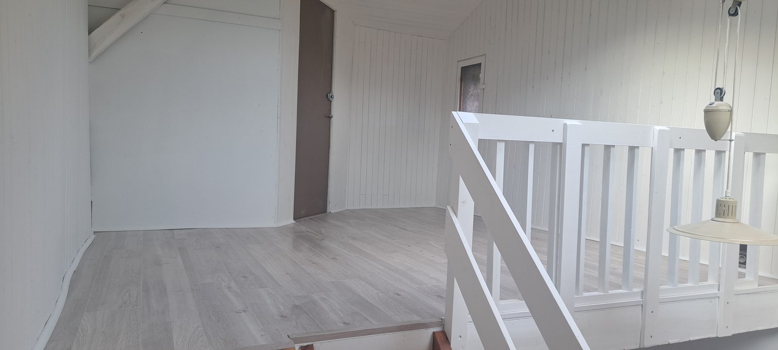 Palier de mezzanine rénové à Eybens : sol stratifié chêne clair et garde-corps bois laqué blanc